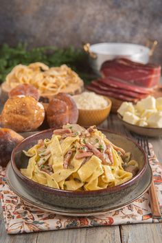 a bowl filled with pasta and meat on top of a table next to other food