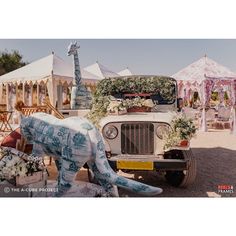 an elephant statue is in front of a truck decorated with flowers and giraffes