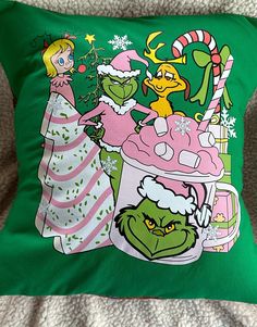 a green pillow with an image of the grinch and snow queen on it's side