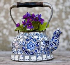 a blue and white tea pot with purple flowers in it