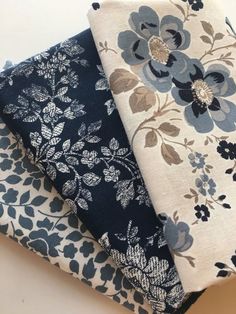 three pieces of blue and white fabric on top of each other, one with flowers