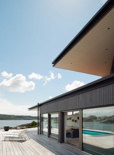 an outdoor deck with chairs and tables next to the water