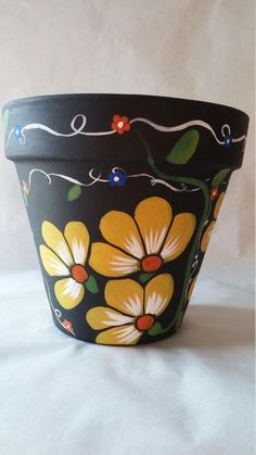 a black flower pot with yellow flowers painted on the side and red lights in the middle