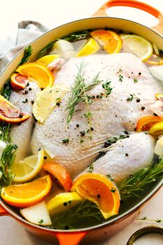 a whole chicken in a pot with oranges and lemons