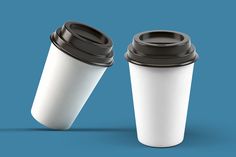 two white coffee cups with black lids on a blue background