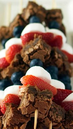 desserts are arranged on sticks with strawberries and blueberries