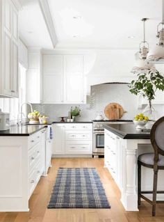 a kitchen with white cabinets and black counter tops, an area rug on the floor