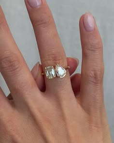 a woman's hand holding an engagement ring with two stone stones on the side