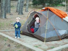 two small children standing in a tent on the ground