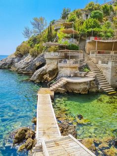 the water is crystal blue and clear with steps leading up to some houses on top of it