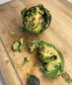 an avocado cut in half on a wooden cutting board with other food items