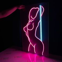 a neon sign with a woman holding a pole in it's right hand, on top of a table