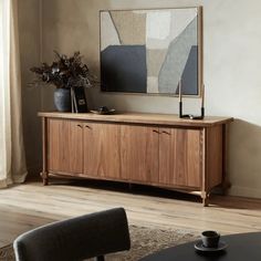 a living room with a large painting on the wall and wooden furniture in front of it