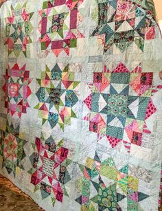 a woman is holding up a quilt on the counter