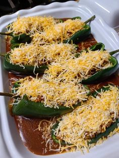 some green peppers covered in cheese on a white platter with a knife and fork