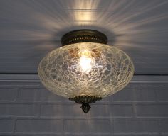 a light that is hanging from the ceiling in a room with brick wall behind it