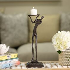 a table with a candle and some books on it next to a vase filled with flowers