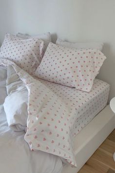 a bed with white sheets and pink hearts on it's pillowcase, in a bedroom