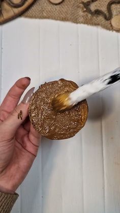 a person is holding a brush and painting something brown on the surface with white paint