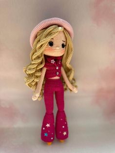 a small doll with blonde hair wearing pink boots and a knitted hat is standing in front of a white background