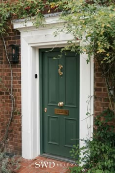 a green front door on a brick building with ivy growing around it and the words swd written in gold