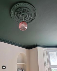 the ceiling in this room is painted green and has a pink lamp hanging from it