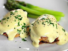 two eggs benedicts on a plate with asparagus