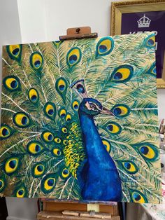 a painting of a peacock with feathers on it's back is shown in an easel