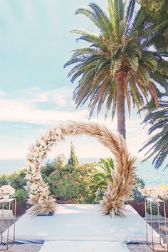 an outdoor ceremony setup with flowers and palm trees