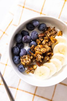 a bowl filled with granola, bananas and blueberries on top of a table