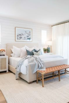 a white bed sitting next to a wooden bench in a bedroom on top of a rug