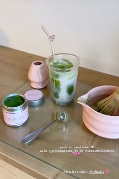 a table topped with two cups filled with green liquid and spoons next to each other