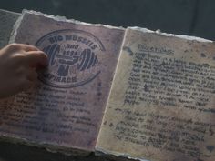 an old book with writing on it being held up by someone's hand over the page