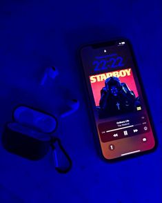 an iphone with the starboy app on it next to ear buds and headphones