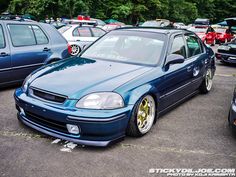 a blue car parked in a parking lot next to other cars