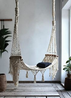 a white hammock hanging from a ceiling in a room with potted plants