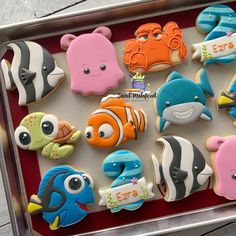 there are many decorated cookies in the tray on the table, including fish and sea animals