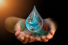 a hand holding a water drop with the earth in it