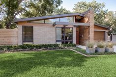 a modern house with grass and trees in the background