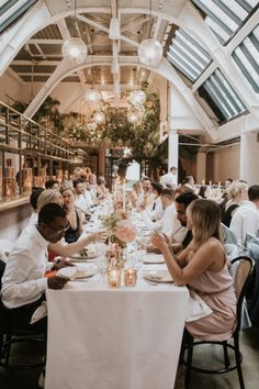 a group of people sitting at tables in a room with high ceilings and glass windows