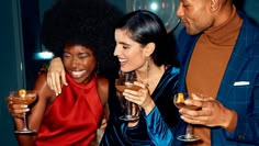 two women and a man are holding wine glasses