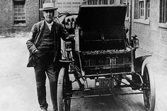 an old black and white photo of a man standing next to a horse drawn carriage