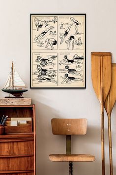 an old poster hangs on the wall next to a wooden chair and desk with paddles