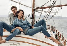 two people sitting on the deck of a sailboat