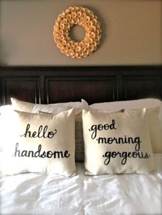 two pillows that are on top of a bed with a wreath hanging above the headboard