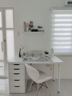 a white desk with a computer on top of it next to a window covered in blinds