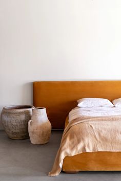 a bed sitting next to two vases on the floor