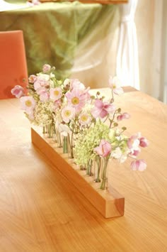 a wooden table topped with vases filled with pink and white flowers on top of it