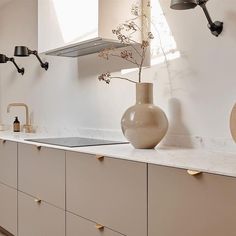 a vase with flowers is sitting on the counter in this white and beige kitchen area