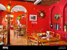 the inside of a restaurant with red walls and wooden tables, chairs and pictures on the wall